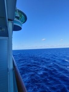 Scene of the ocean and sky along the side of a cruise ship at sea